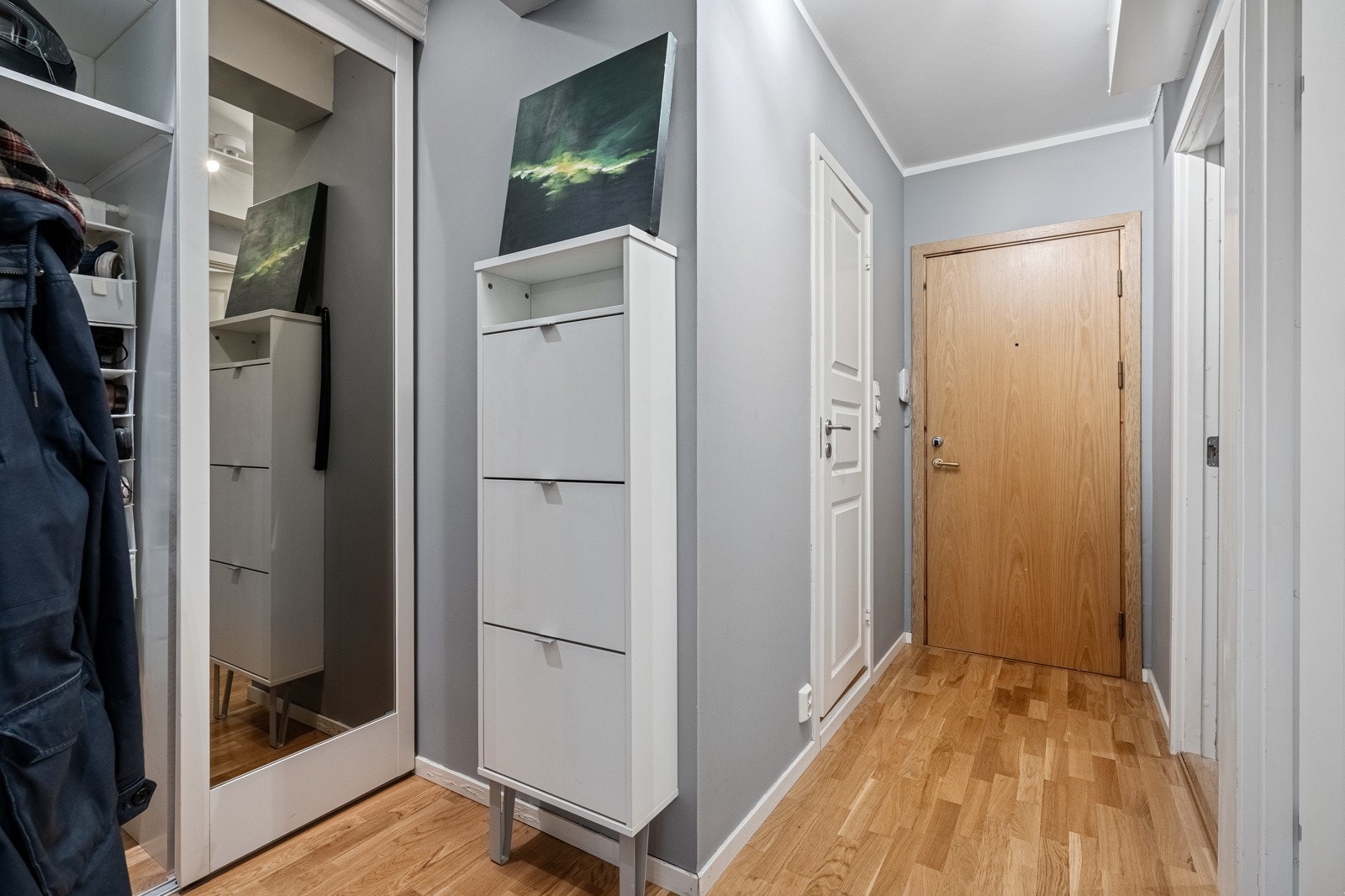 Langstrakt entré med garderobeløsning for yttertøy og sko, samt tilkomst til leilighetens øvrige rom. Galleribilde