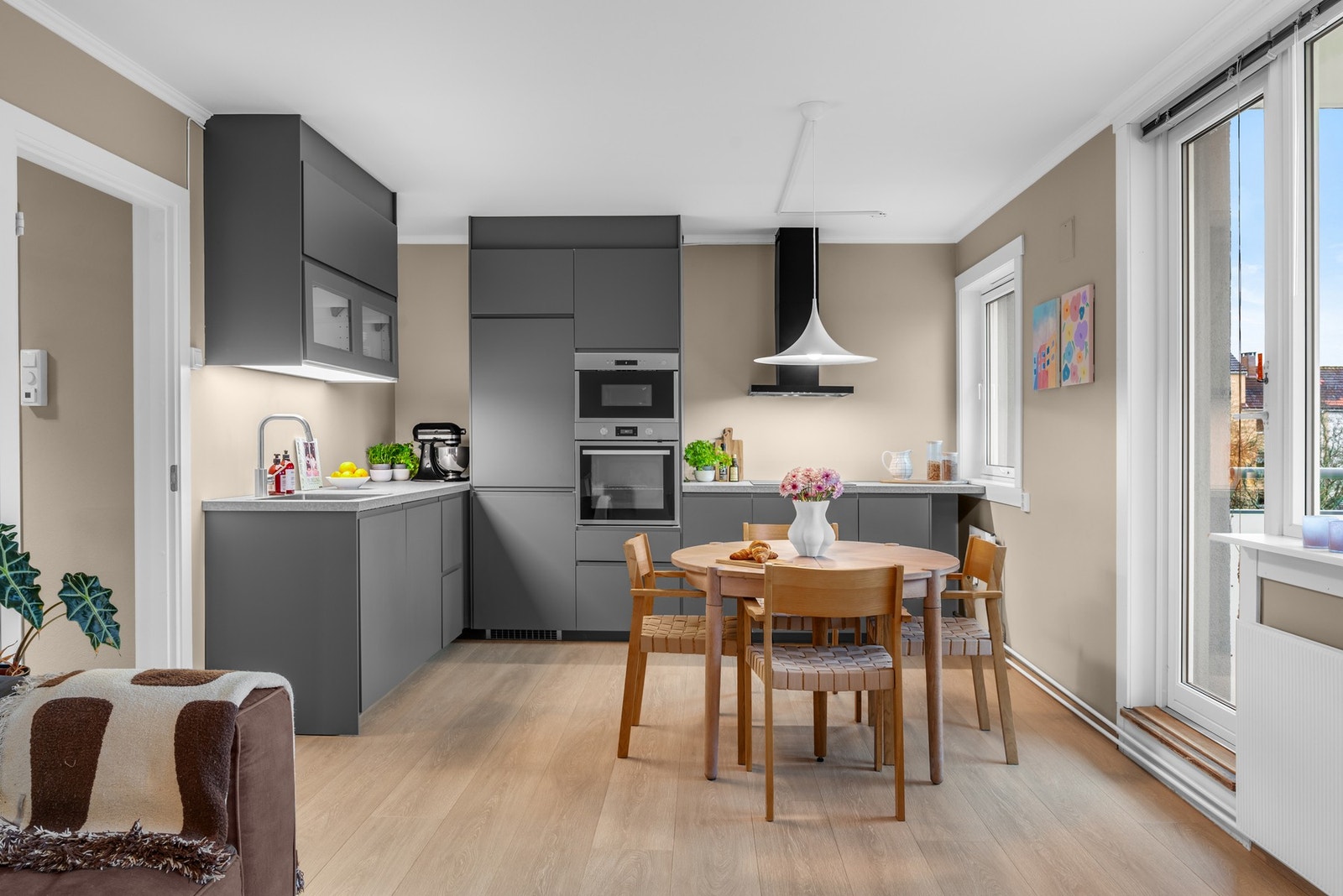 Ikea-kjøkkenet fra 2021 er stilrent og moderne, oppført i en funksjonell L-form med glatte, mørkegrå fronter, dempefunksjoner, to små vitrineskap og oppvaskkum av stål nedfelt i en laminert benkeplate. Galleribilde