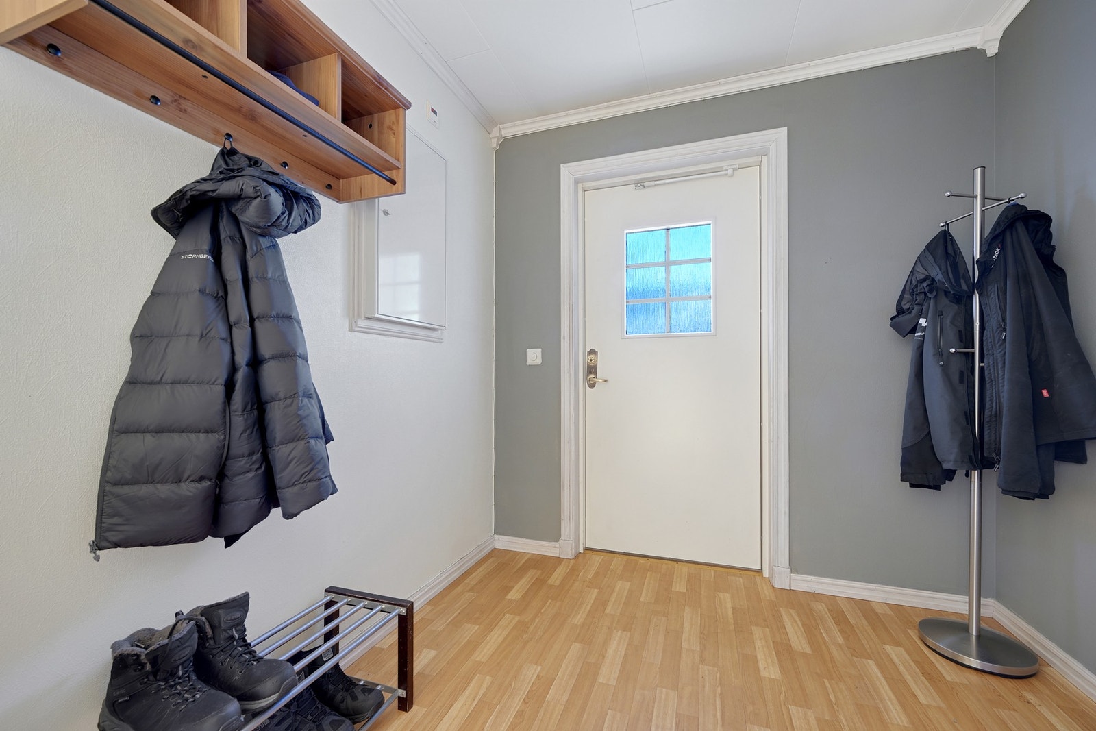 Entré med parkettgulv og lyse vegger. Vegghengt hylle og knagger gir gode oppbevaringsmuligheter. Galleribilde