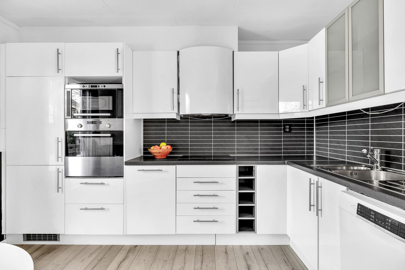 Stilrent IKEA kjøkken fra 2010 med hvite, glatte fronter og laminert benkeplate. God belysning og smarte stikkontakter under overskap Galleribilde