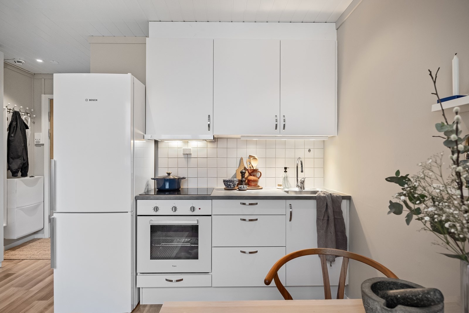 Moderne og stilrent kjøkken med glatt, laminert kjøkkeninnredning, fliser mellom overskap, og en slitesterk laminert benkeplate. Galleribilde