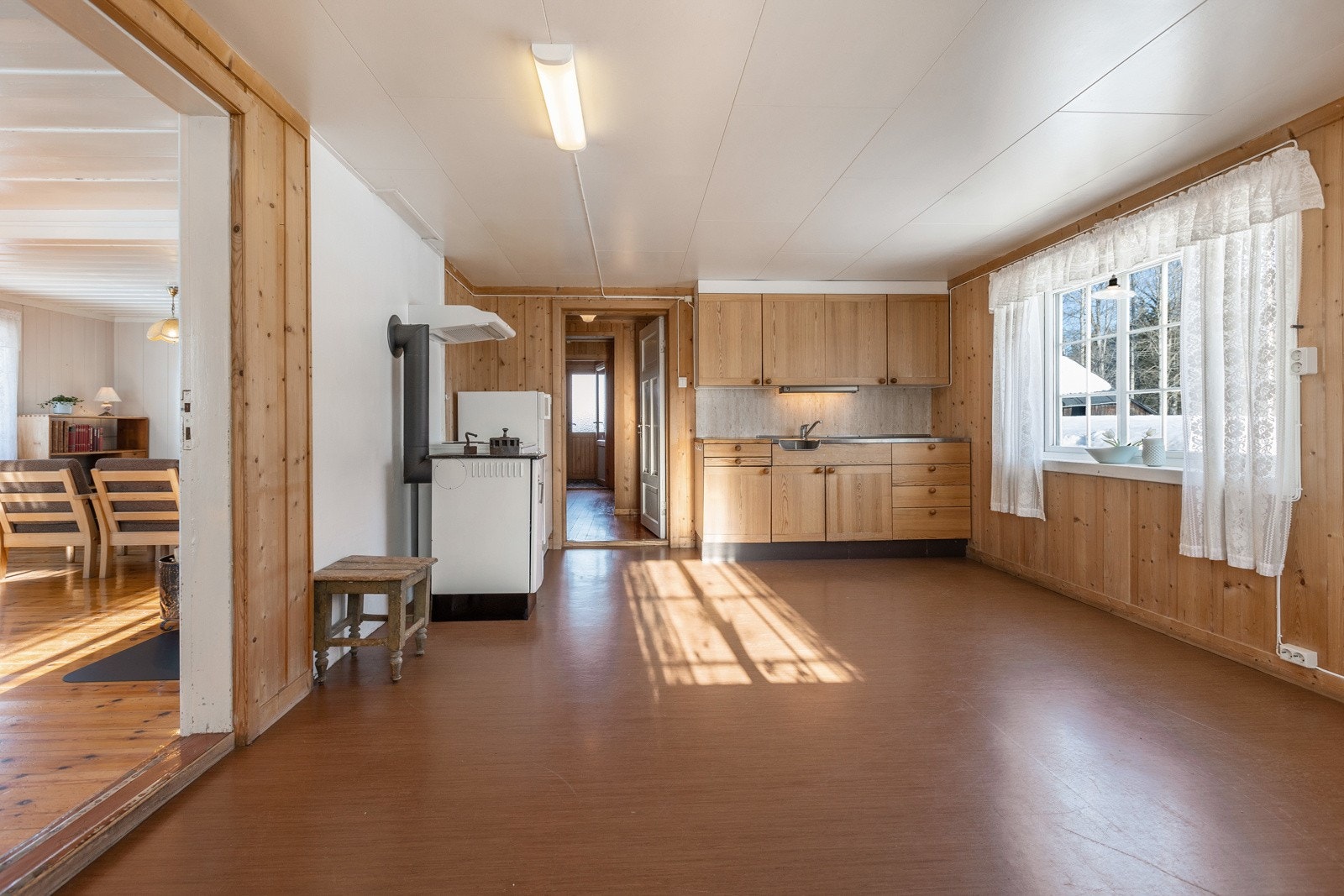 Eldre innredning med laminat fronter og benkebeslag. Rommet er stort nok til å utvide kjøkkeninnredningen. Frittstående komfyr og kjøleskap samt eldre ovn. Galleribilde