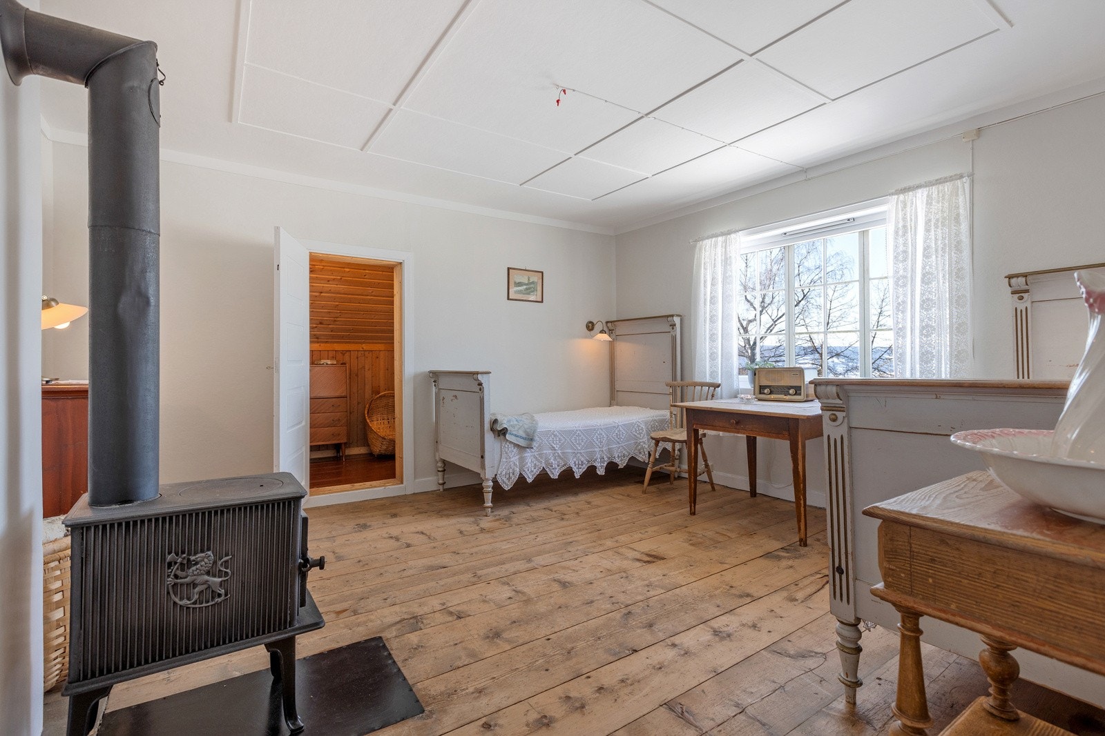 Soverommet i den eldste delen, bredt eldre tregulv og behandlede vegger. Inngang til kleskott/skråtak både fra dette soverommet og naborommet. Jøtul vedovn som varmer opp her. Galleribilde