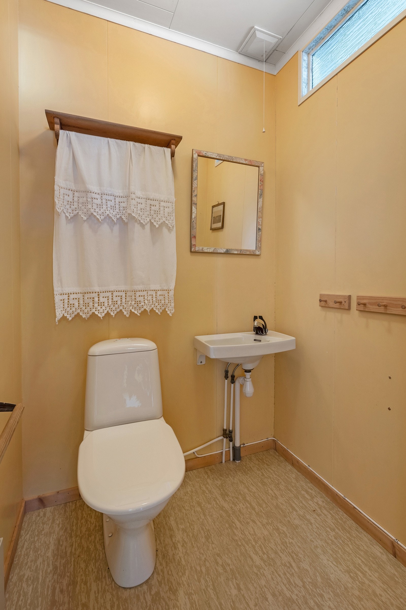 Toalettrom med belegg på gulv og liten håndvask Galleribilde