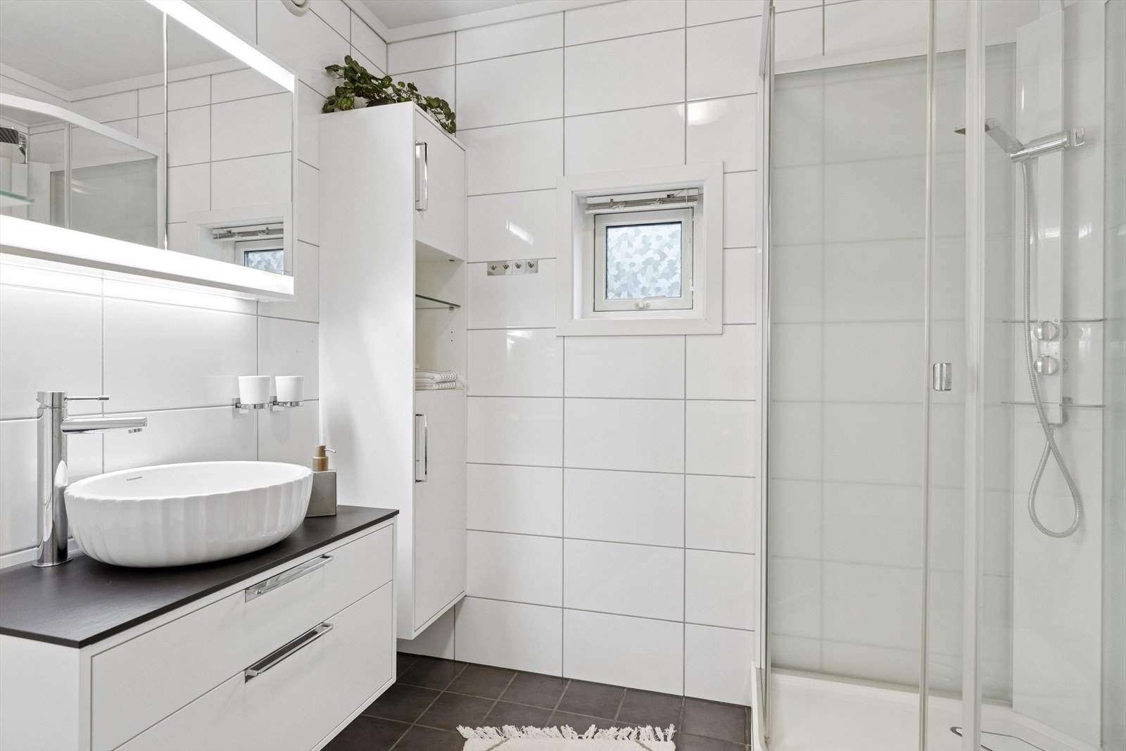 Badet er delikat og helfliset, med et platet og malt tak. Det inneholder toalett, en praktisk innredning med servant og et romslig dusjkabinett. Galleribilde