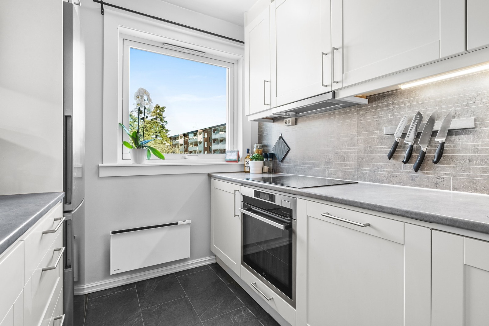 Kjøkkenet er godt utstyrt med integrerte hvitevarer - en platetopp, stekeovn, oppvaskmaskin og kullfilterventilator, samt nisje til kjøleskap. Det er installert automatisk lekkasjestopper til oppvaskmaskinen. Galleribilde
