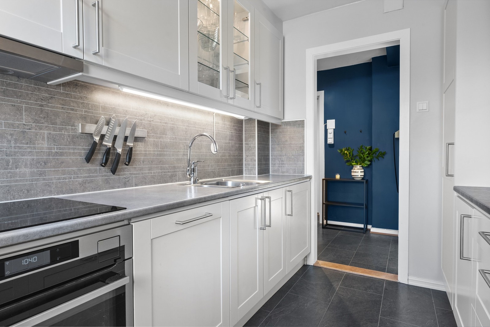 Vaskekummen er underlimt, og det er montert grå flisplater og bra med belysning over benken. Galleribilde