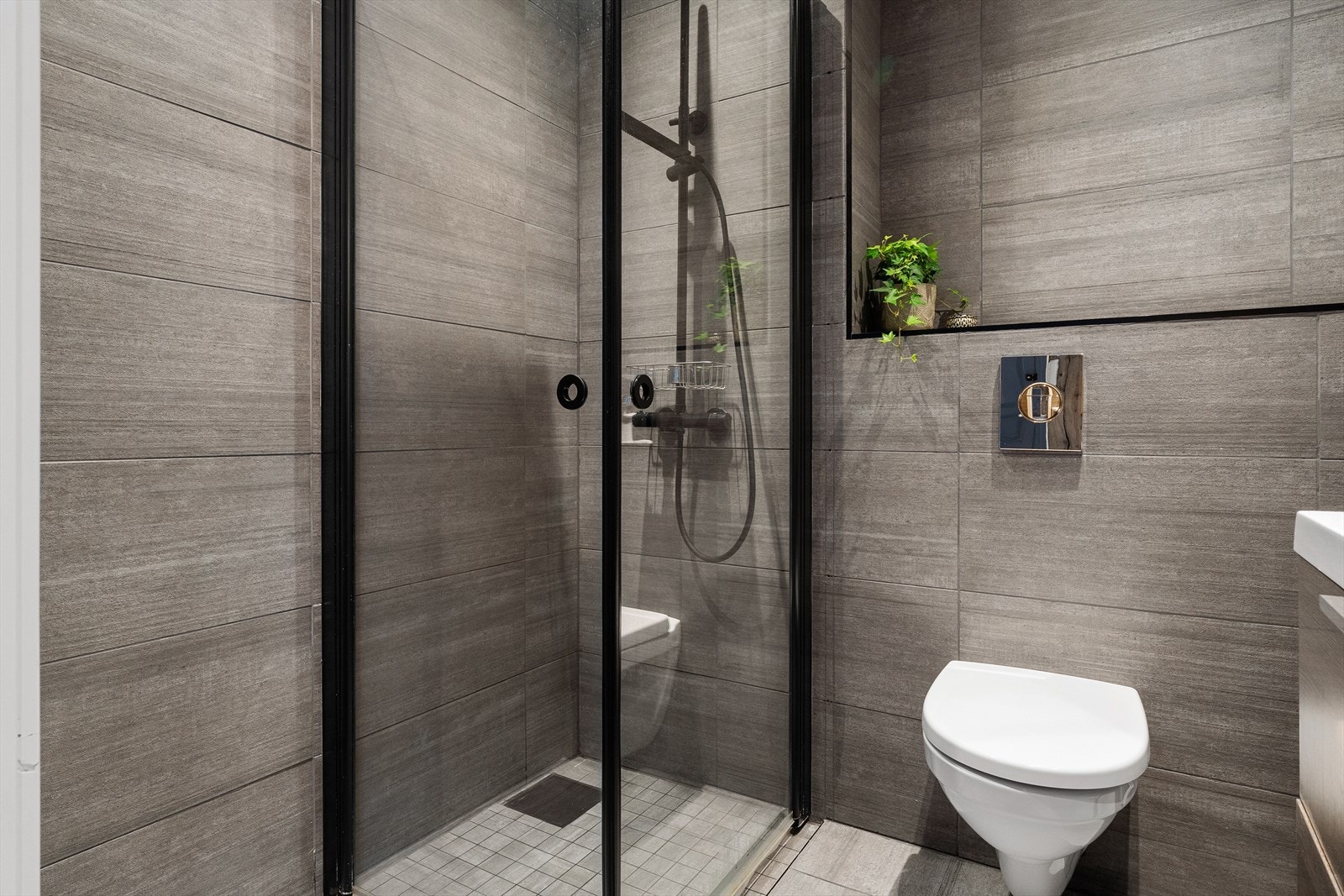 Det er av god størrelse og innredet med servantmøbel, toalett og dusj Galleribilde