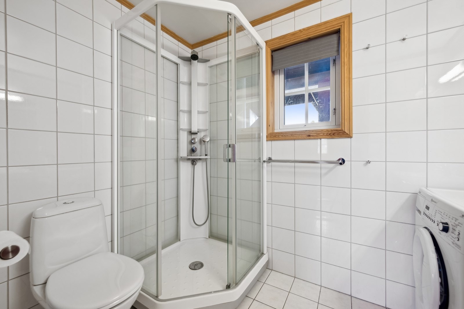 Baderommet i gjestefløyen har tilsvarende standard som badet i hovedfløyen, med fliser på vegger og gulv, toppmontert servant, speil med lysarmatur, dusjkabinett fra Porsgrund Bad, og gulvmontert toalett. Galleribilde