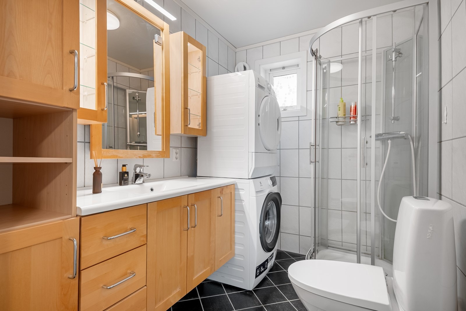 Flott flislagt bad og god plass for oppbevaring. Dusjkabinett og opplegg for vaskemaskin og tørketrommel. Galleribilde