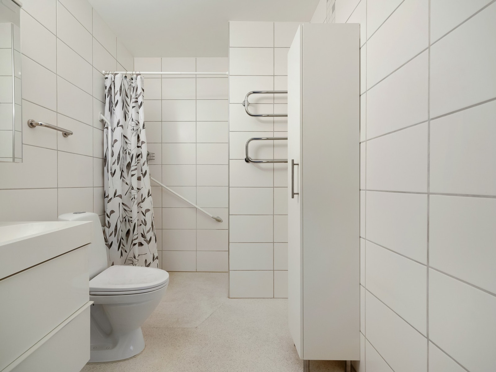 Badet er innredet med dusjhjørne med forheng, gulvstående toalett og servant med speilskap. Galleribilde