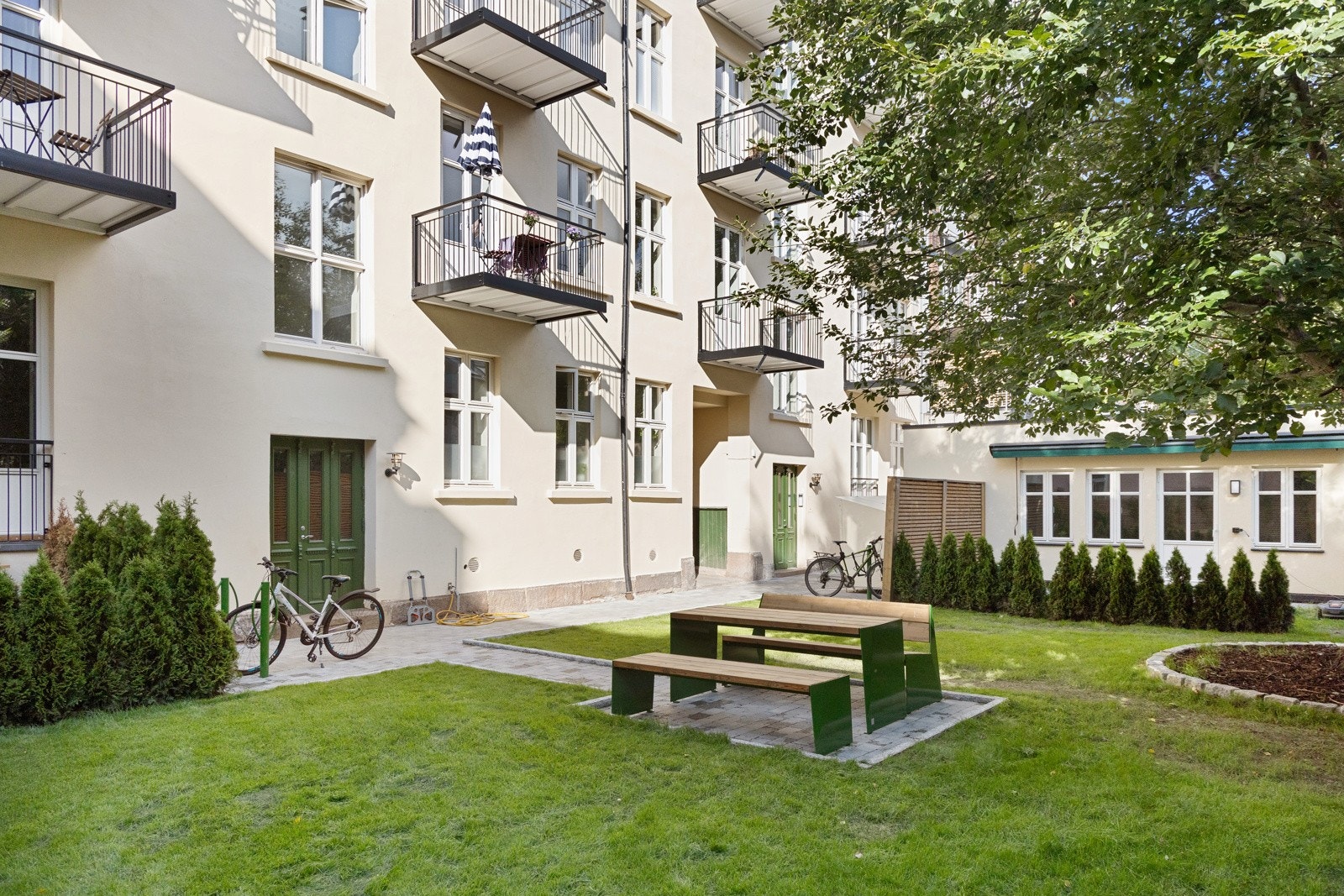 Borettslagets idylliske hage med sittegrupper, benker, sykkelpakering, m.m. Galleribilde