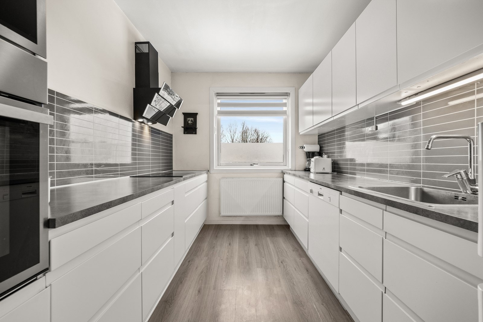 Her har du glatte fronter med innfreset grep og praktisk kitchenboard over benkeplate Galleribilde