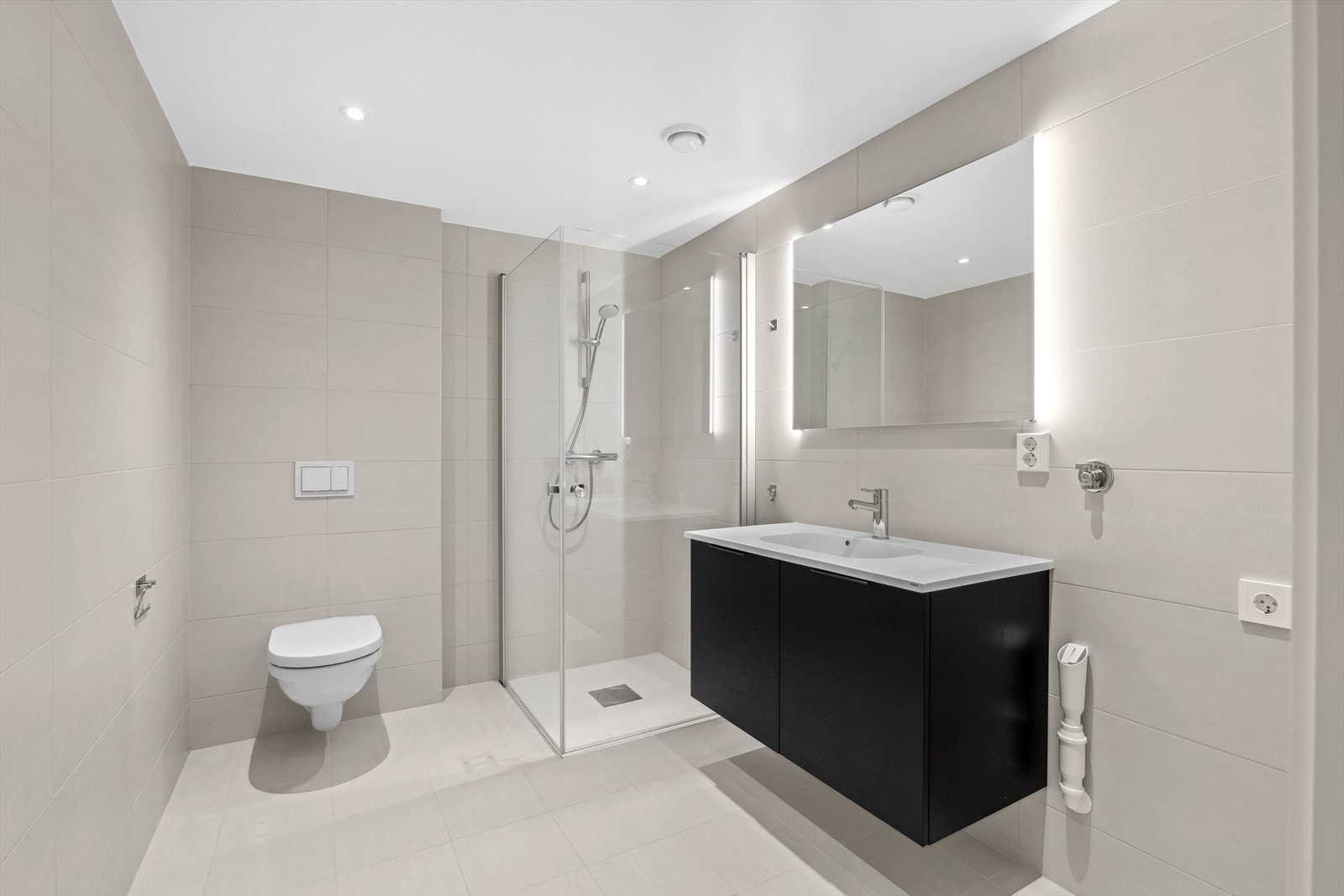Badet er flislagt med smakfulle og tidløse fliser på gulv og vegger og har tilhørende moderne baderomsinnredning. Galleribilde