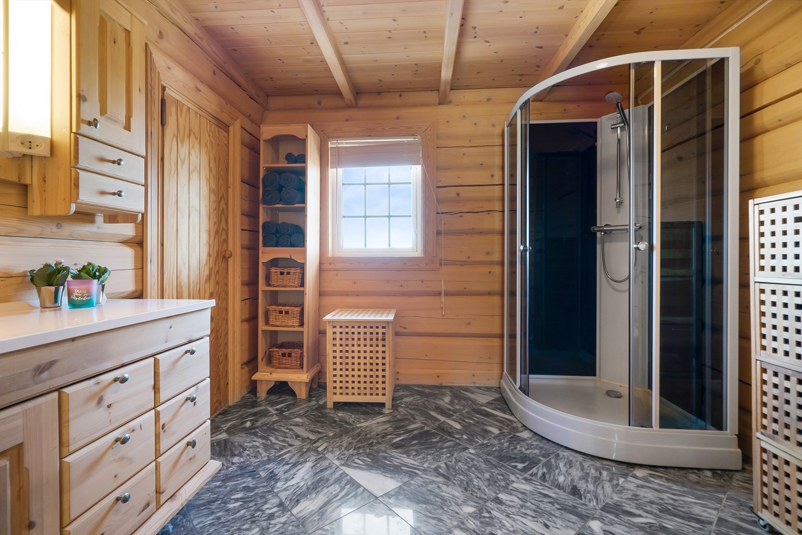 Det ene badet i 1. etasje med badstue. Tømmervegger, panel i tak og marmorfliser på gulv Galleribilde