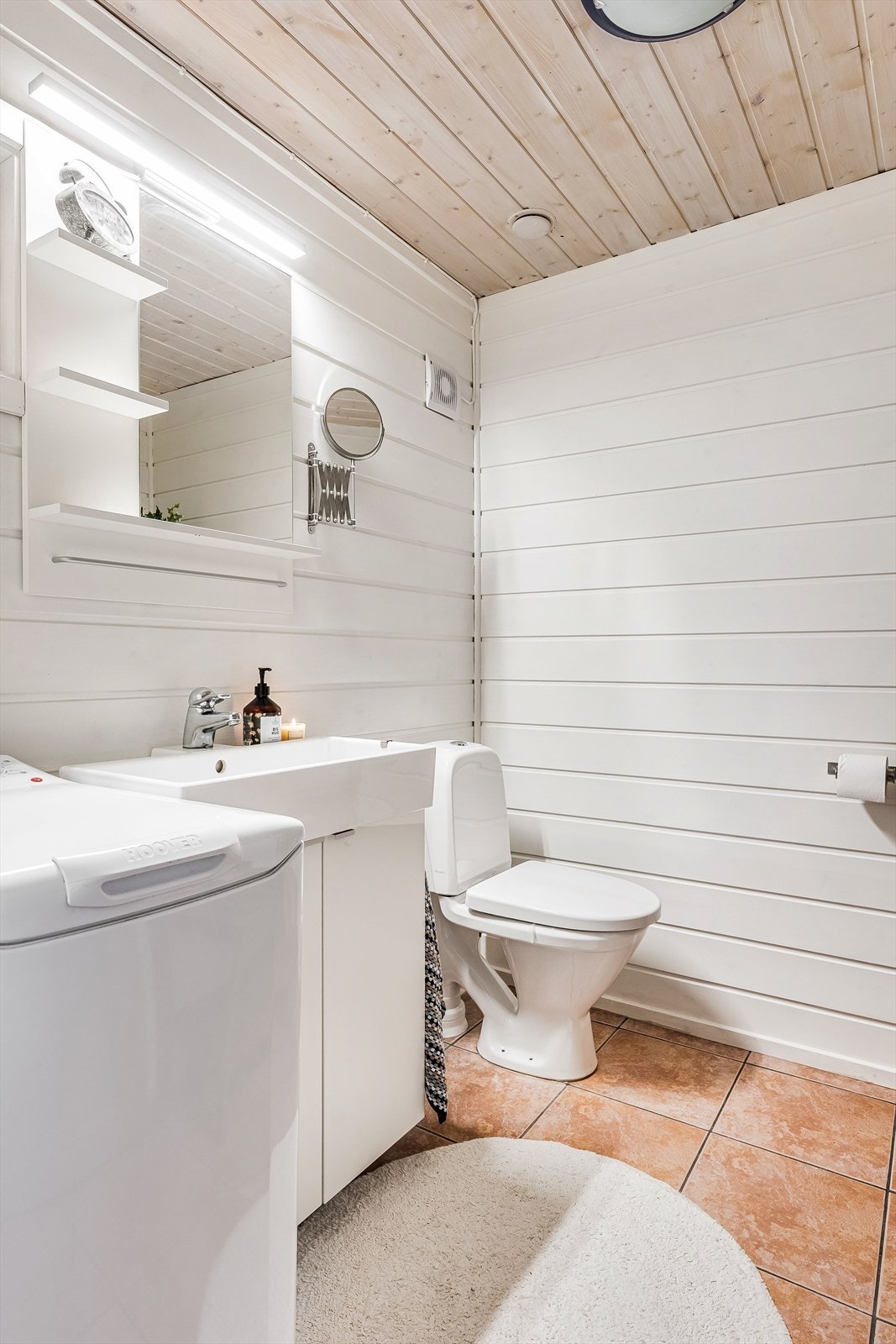 Innredning med wc og heldekkende servant på underskap med speil og belysning over. Vaskemaskinen medfølger i salget. Galleribilde