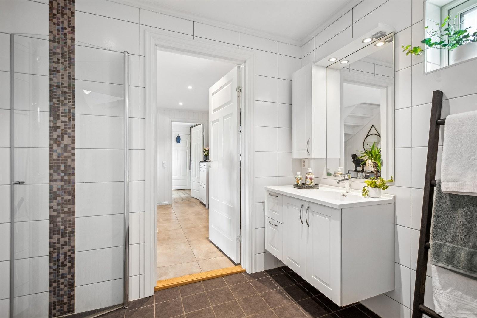 Badet er pent flislagt med varmekabler i gulv. Videre er rommet innredet med dusjnisje med innfellbare glassdører, vegghengt toalett (med ekstra funksjon for tablettrengjøring) og servantinnredning med speilskap. Galleribilde