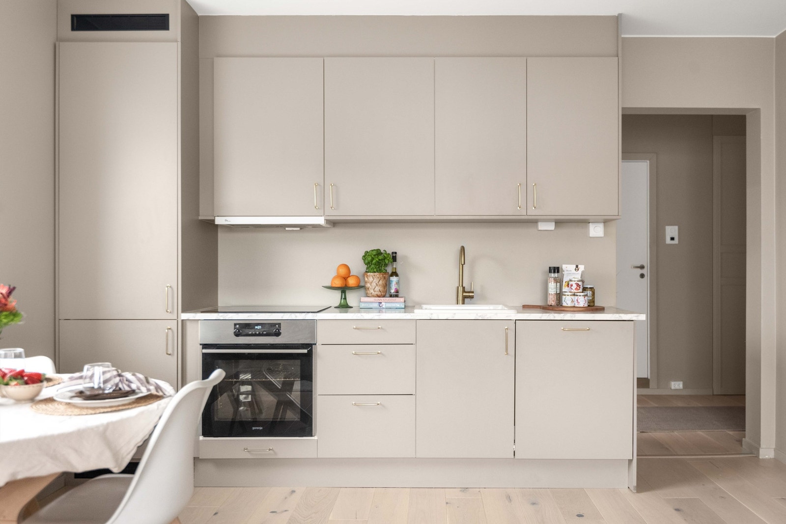 Kjøkkenet har en åpen løsning til stuen som gjør rommet til et sosialt sted med plass til både et lite spisebord, sofagruppe, TV, TV-benk, og annet interiør som reflekterer egen stil. Galleribilde