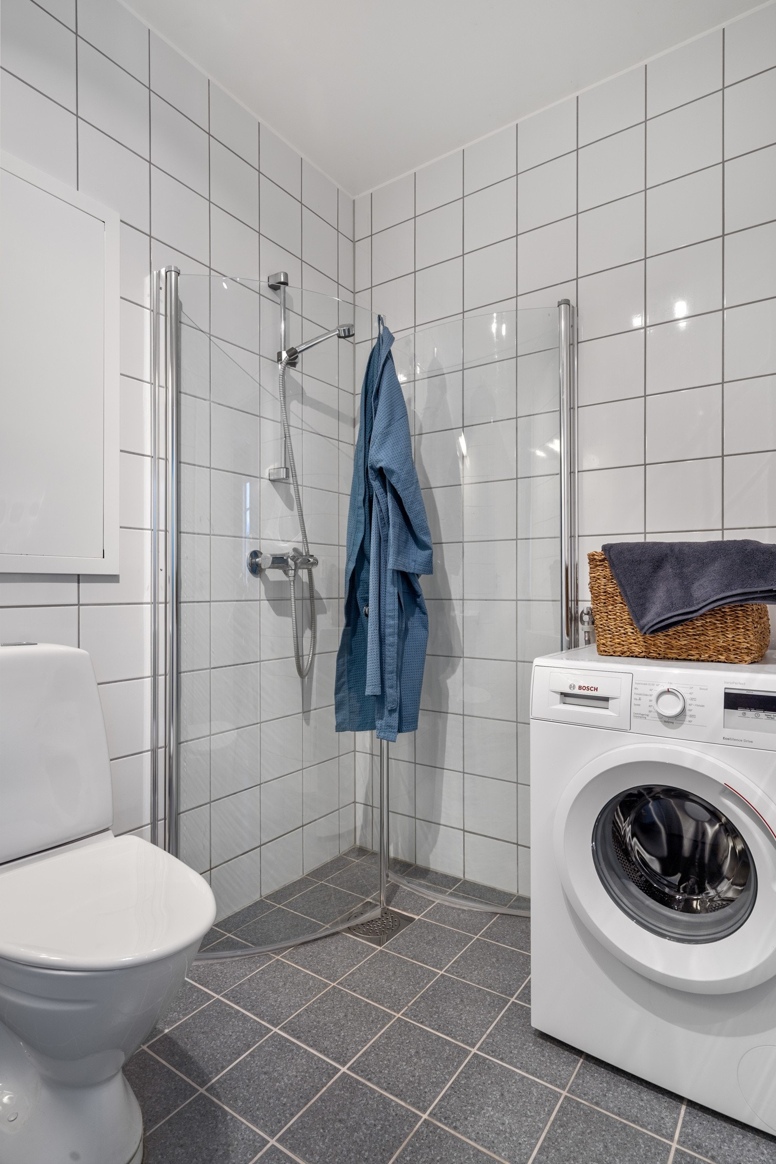 Badet er videre innredet med dusjhjørne med innfellbare dusjvegger, opplegg for vaskemaskin, toalett og servant med underskap. Galleribilde