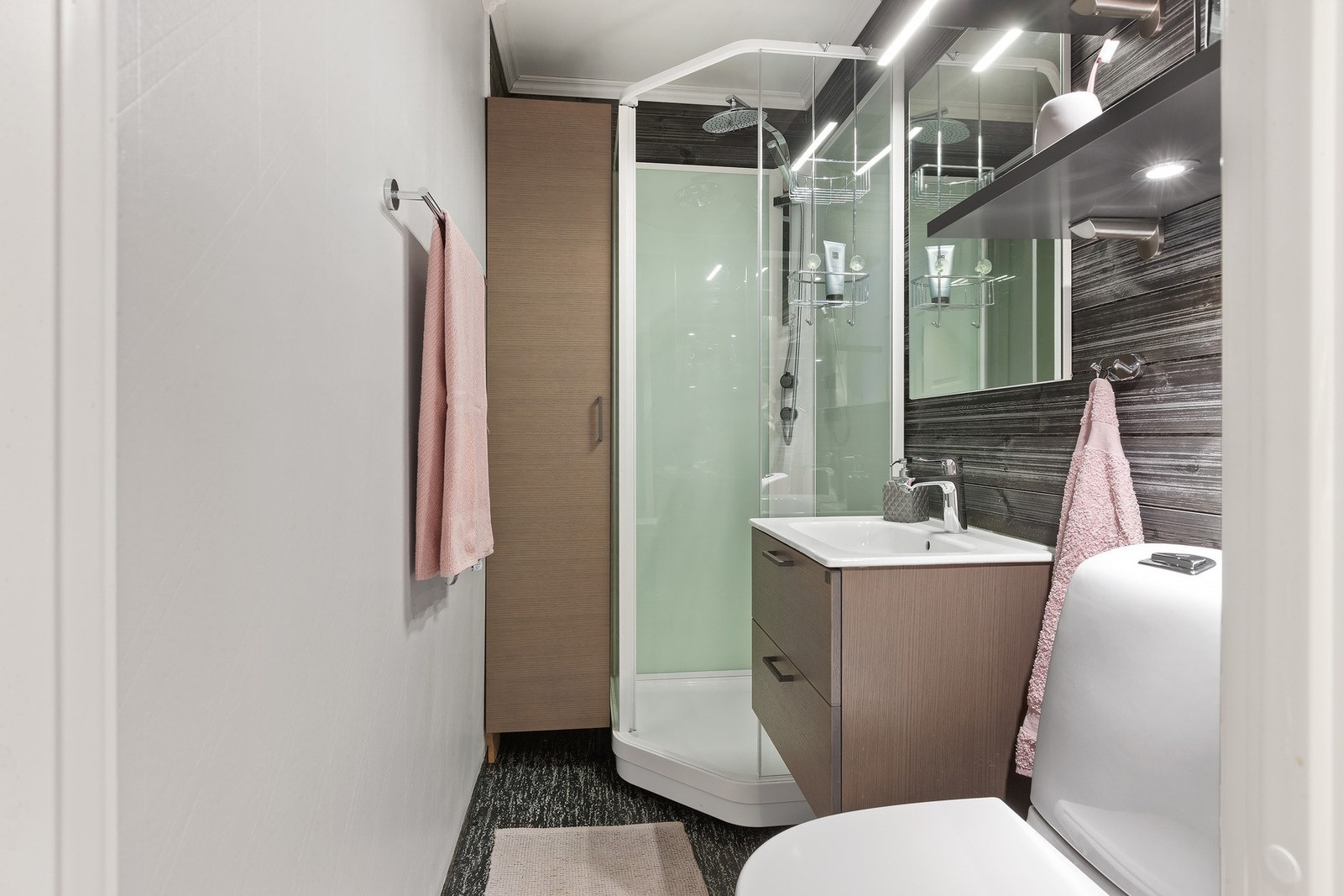 Badet har servantinnredning med speil og overlys, høyskap med mulighet for oppbevaring, toalett og dusjkabinett. Galleribilde