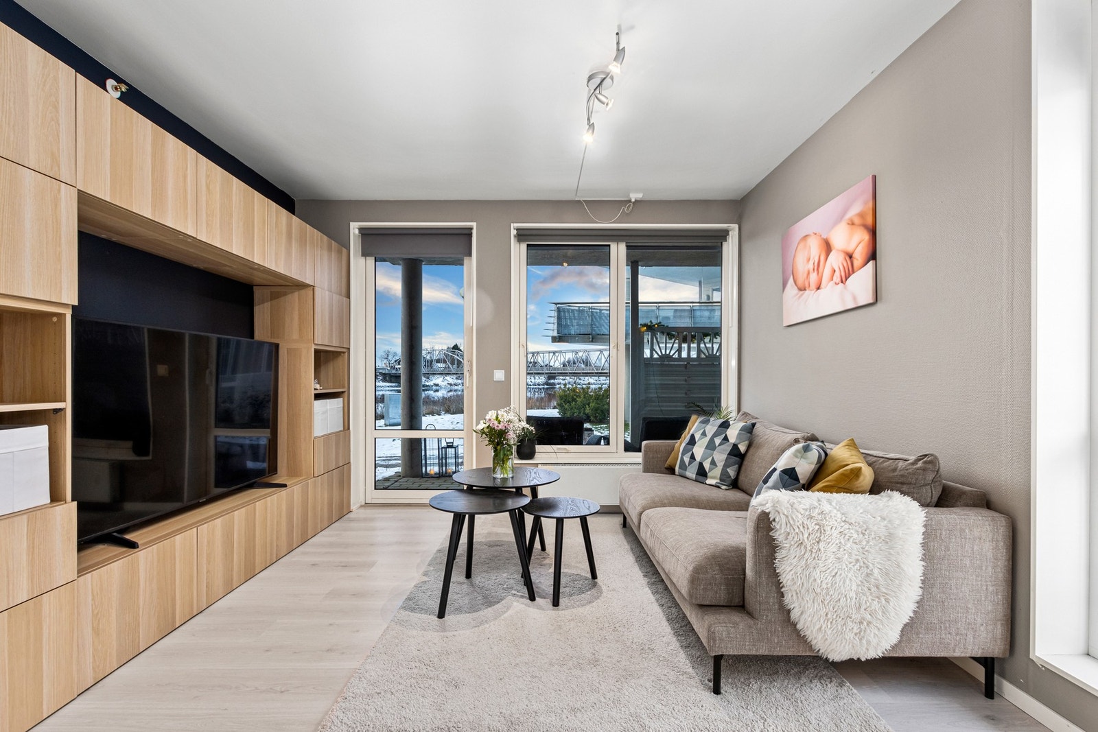 Stue med utgang til vestvendt uteplass. Her har man utsikt over elva. Lagringsreol rundt tv følger med på kjøpet. Galleribilde