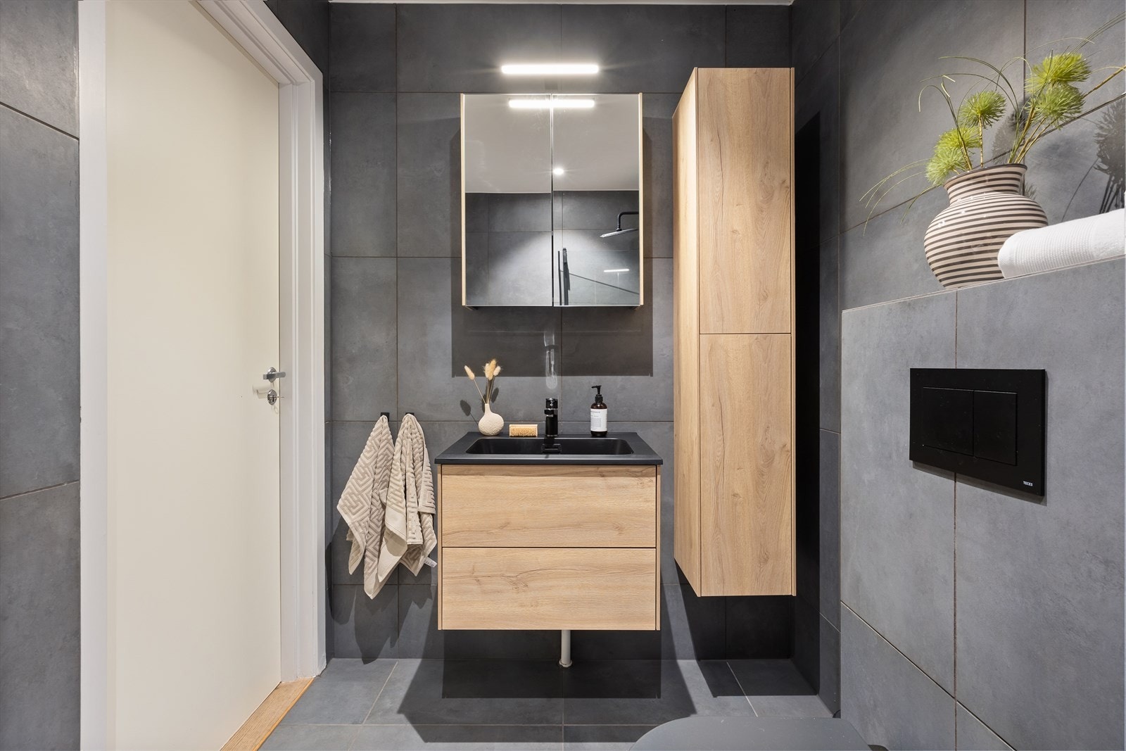 Baderommet er innredet med nedfelt servant, veggmontert toalett og dusjvegger/hjørne. Galleribilde