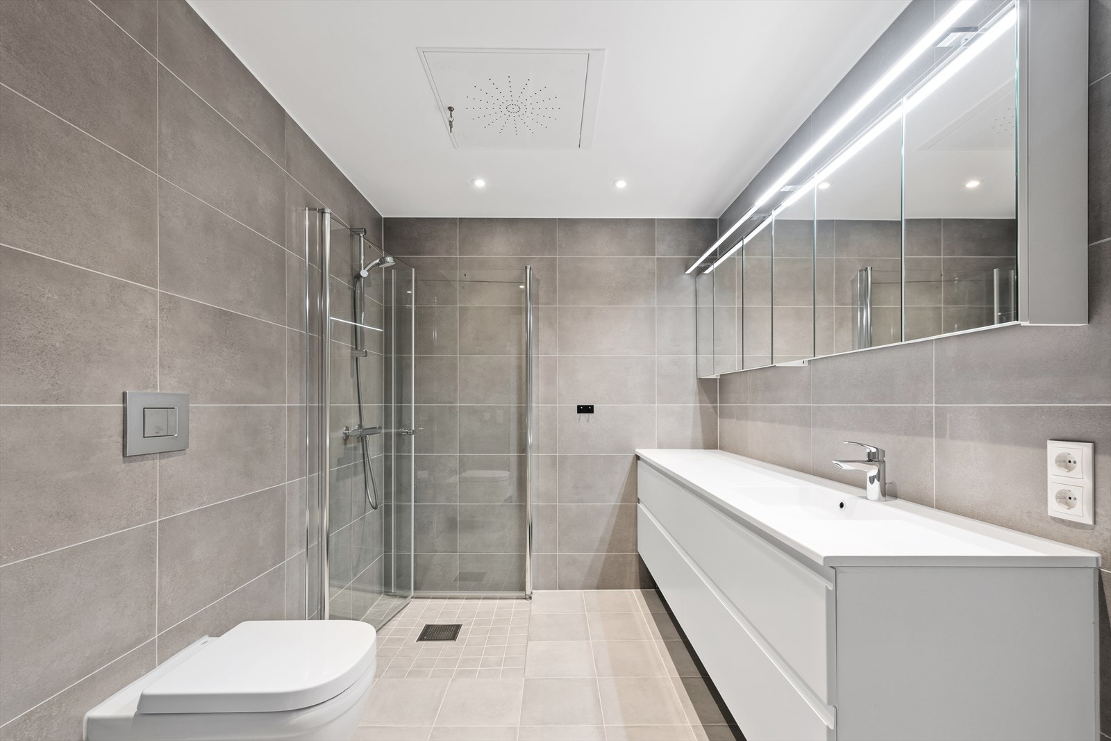 Delikat flislagt bad med varme i gulvet og downlights i himlingen Galleribilde