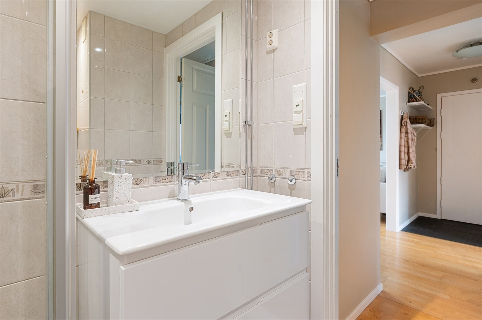 Baderomsinnredning med glatte fronter og speil montert på vegg. Vegghengt toalett og innfellbare dusjvegger. Galleribilde