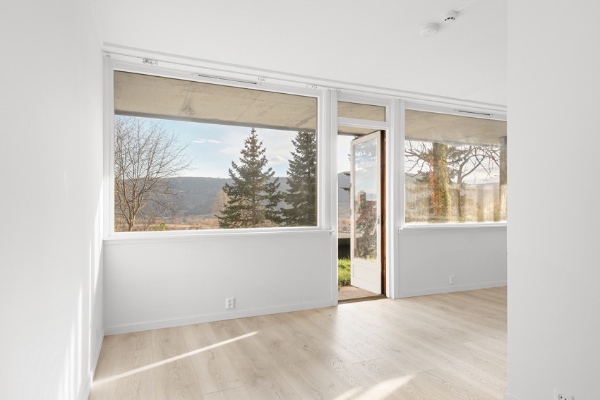 Romslig stue med store vinduer og utgang til uteområde Galleribilde