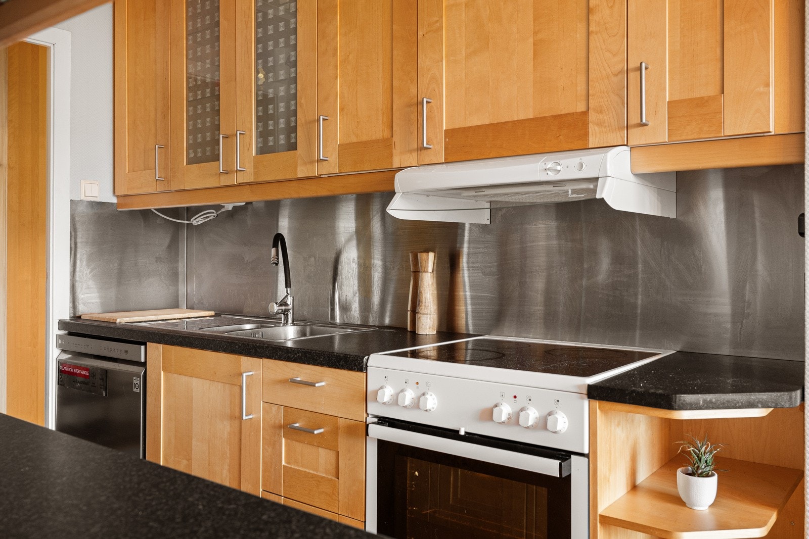 Kjøkkenet har profilerte trefronter, og over den ene benken er aluminiumsplater montert for beskyttelse. Galleribilde