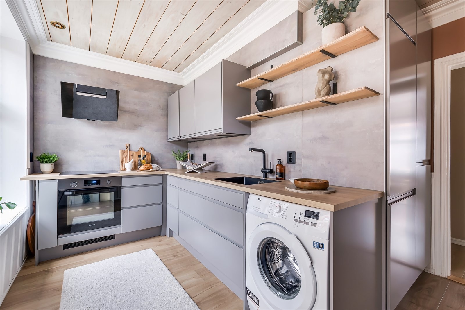 Kjøkkenet er moderne med stilrene fronter og integrerte løsninger. Den varme benkeplaten skaper en fin kontrast til de elegante gråtonene. Galleribilde