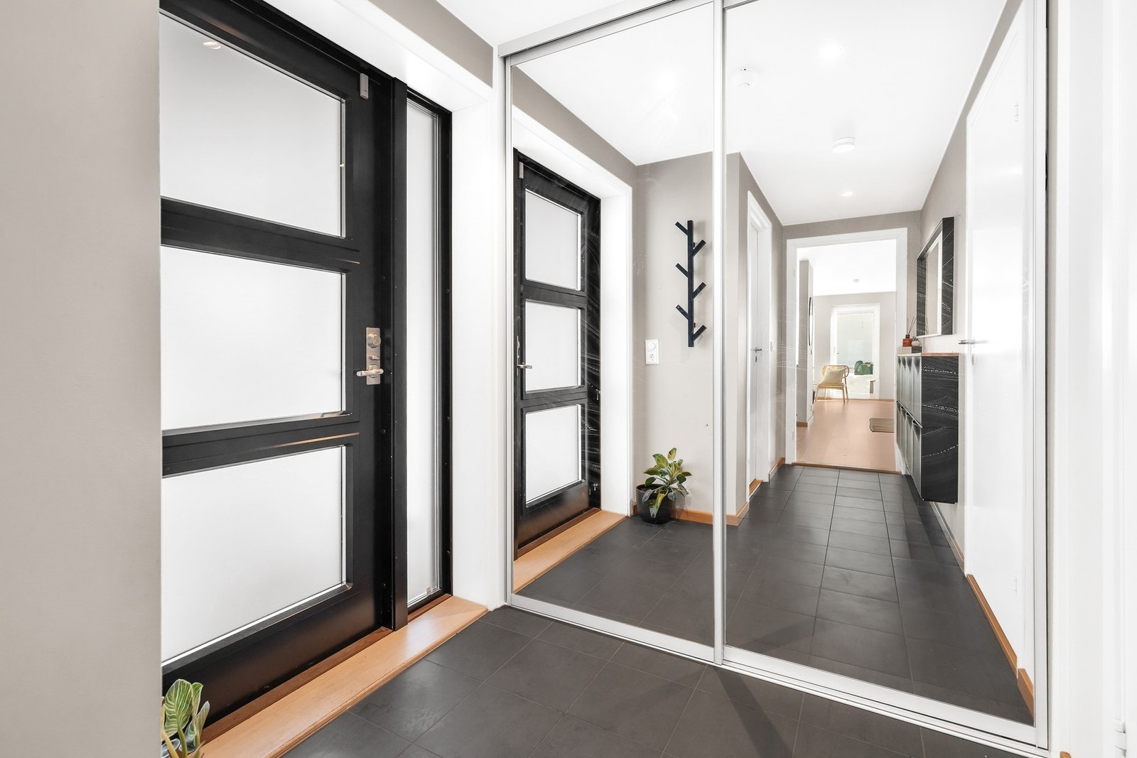 Fin entré med flislagt gulv og fin plass til oppbevaring av yttertøy og sko i skyvedørsgarderobe Galleribilde