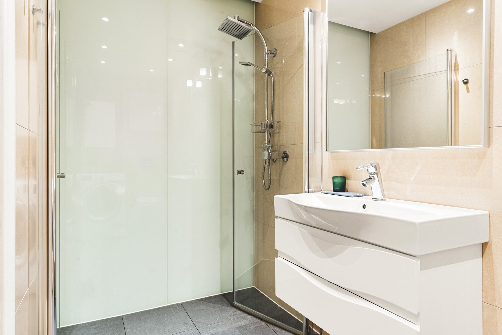 Badet er innredet med dusj m/glassvegg, vegghengt toalett, baderomsinnredning og opplegg for vaskemaskin. Galleribilde
