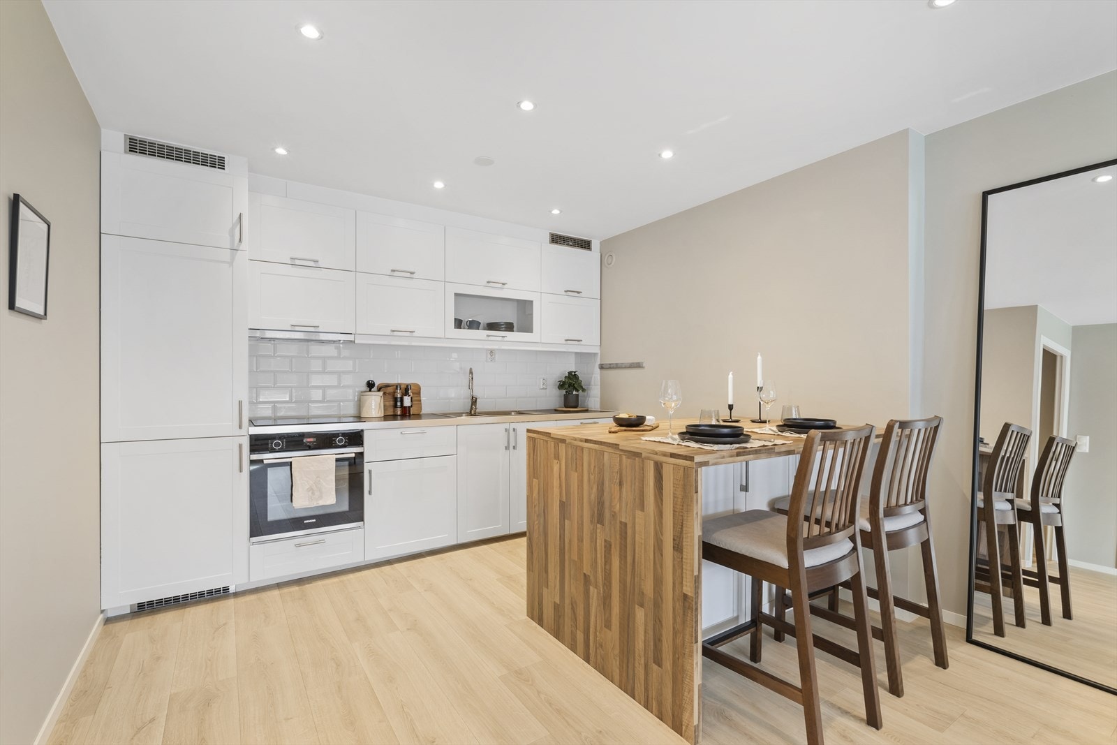 Kjøkkeninnredning med profilerte fronter, ett overskap har glassfront, laminat benkeplate, over benkeplaten er det benyttet fliser, stål oppvaskkum, ventilator Galleribilde