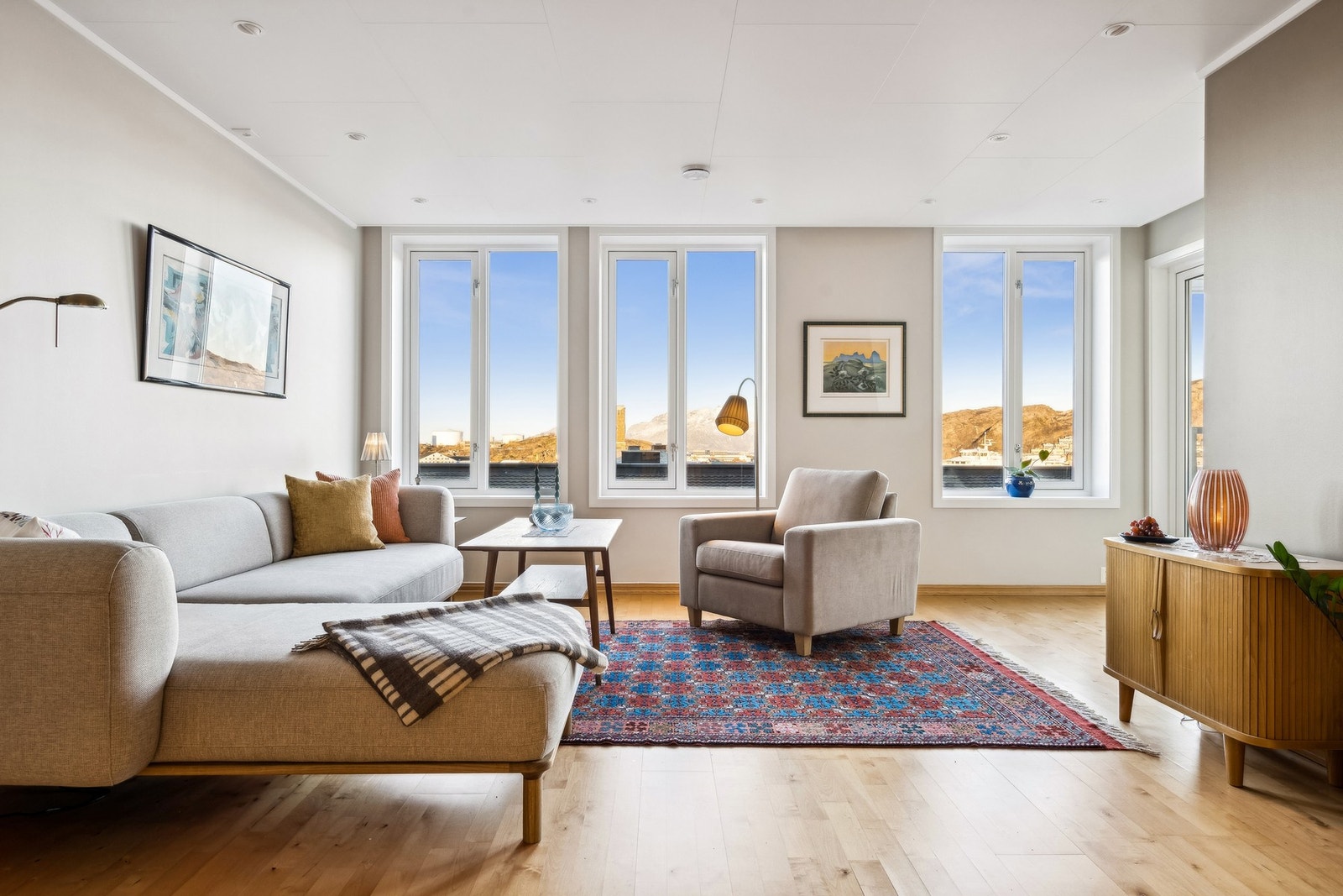 Stuen er lys og trivelig, med store vindu mot sjøen som slipper inn flott naturlig lys i leiligheten Galleribilde