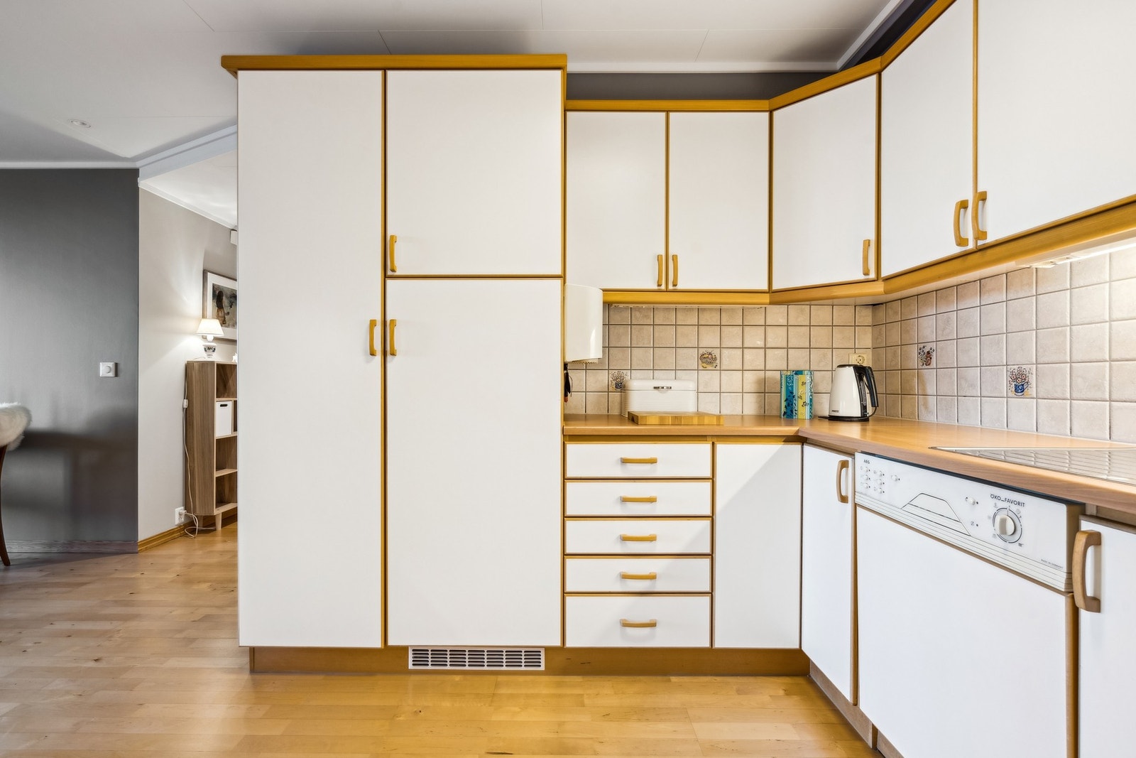 Kjøkken med innebygget kjøleskap, komfyr og oppvaskmaskin. Fliser mellom benk og overskap Galleribilde