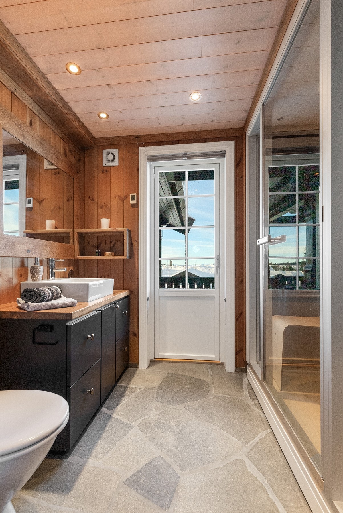 Dette badet inneholder baderomsinnredning med oppbevaring under, heltre benkeplate med porselenvask, toalett og frittstående dusjkabinett/steamdusj. Terrassedør ut til terrassen Galleribilde