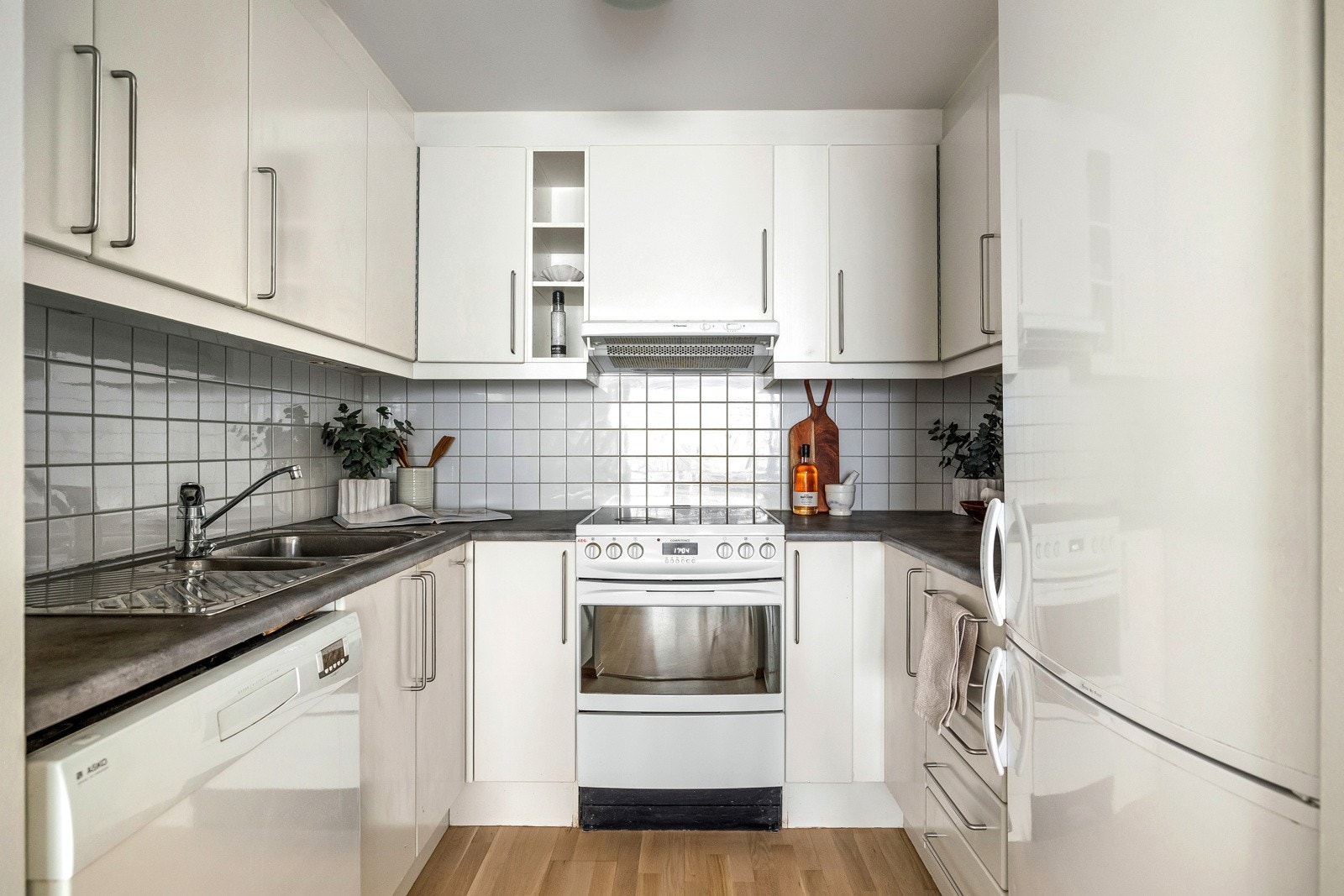 Benkeplaten er laminat med en nedfelt stålkum. Bak kjøkkeninnredningen er det fliser på veggen. Galleribilde