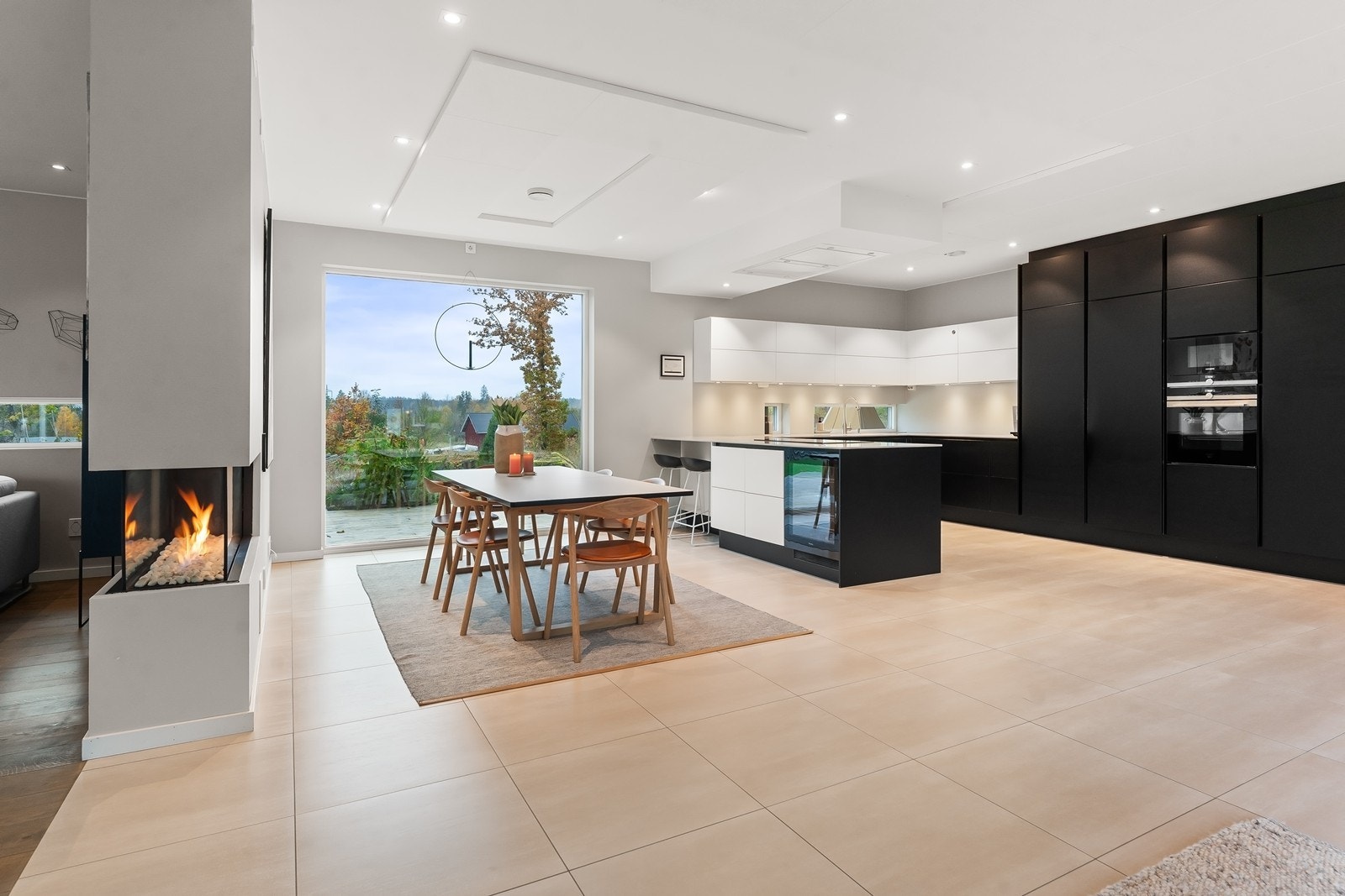 Stort kjøkken med god spiseplass og en klassisk gasspeis som fungerer som en hyggelig romdeler mellom kjøkken og stue. Galleribilde