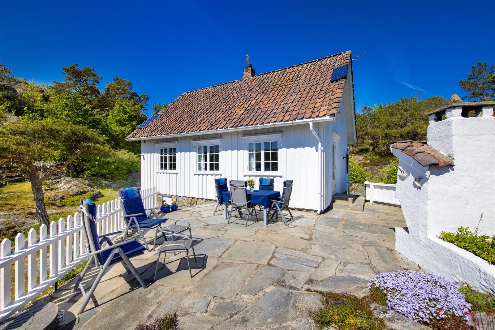 Foran hytta, mot sjøen, er det sørvendt terrasse i skifer med utepeis. Galleribilde