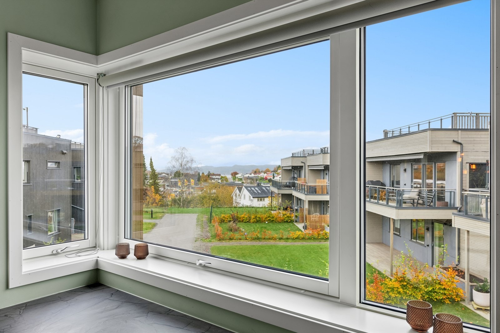 Store vinduer over benkplaten fyller kjøkkenet med naturlig lys, og skaper en varm og innbydende atmosfære. Galleribilde