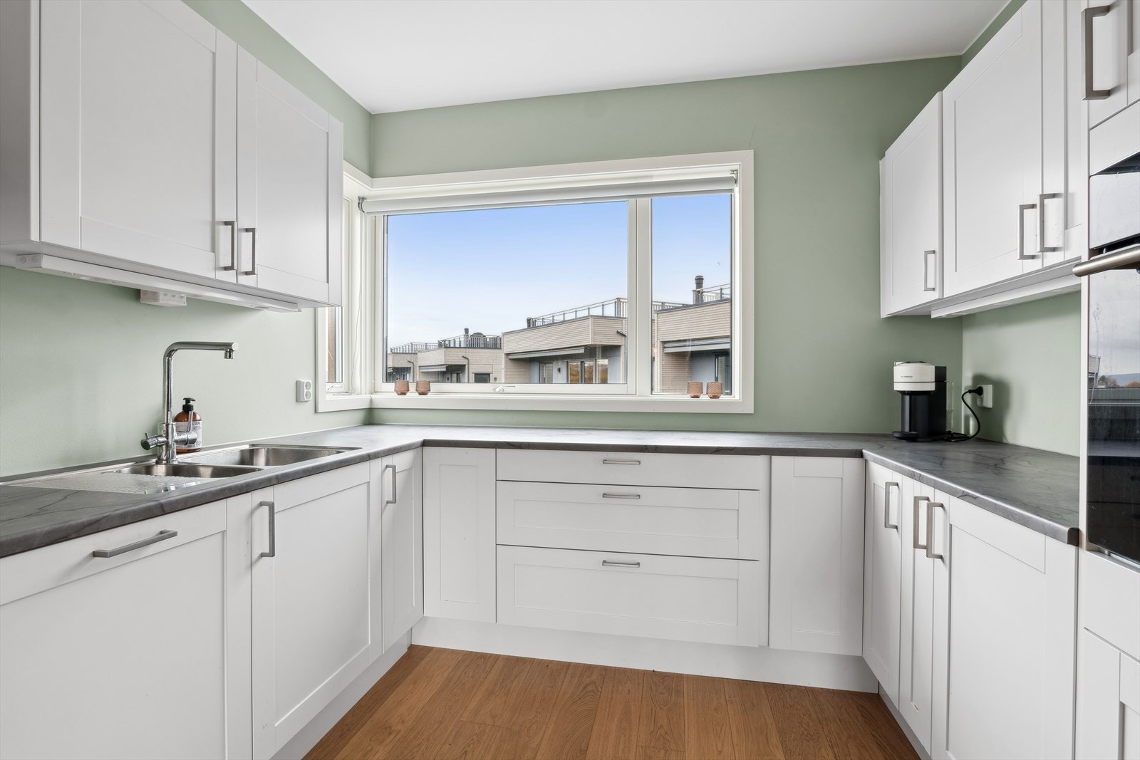 Moderne og velutstyrt kjøkken med hvitmalte profilerte fronter, laminert benkeplate og kjøkkenventilator med avtrekk ut. Galleribilde