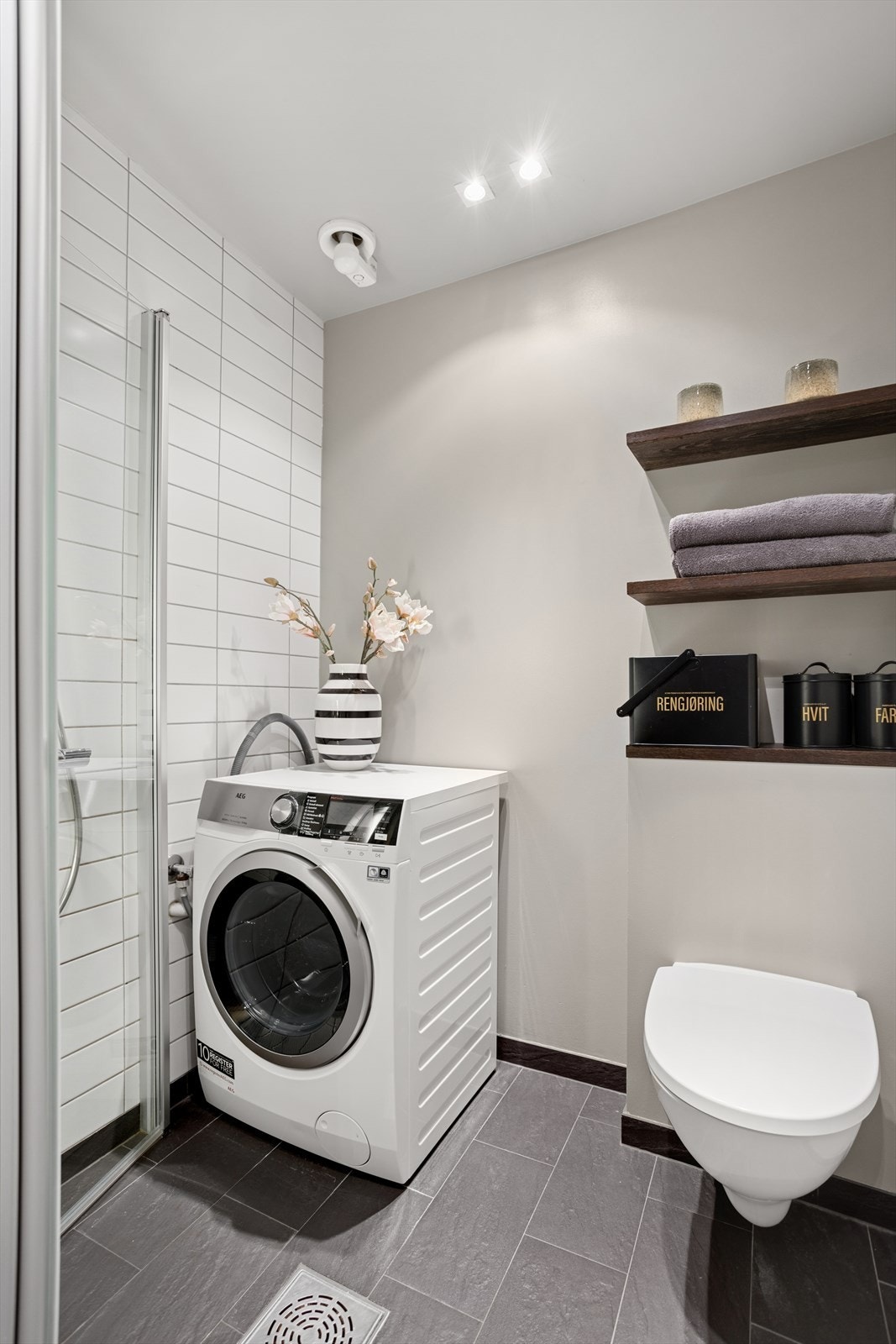 I dag er badet utstyrt med dusj, veggmontert klosett, servant/servantskap, og opplegg for vaskemaskin. Vaskemaskin medfølger salget. Galleribilde