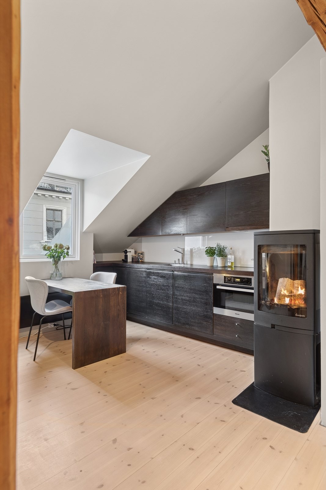 Kjøkkenet har en mørk og tidløs innredning med finerte/beisede fronter. Benkeplaten er også beiset, utstyrt med planlimt oppvaskkum. Integrert i innredningen finner du stekeovn/koketopp, kjøleskap/fryseskap og oppvaskmaskin. Kullfilterventilator. Galleribilde