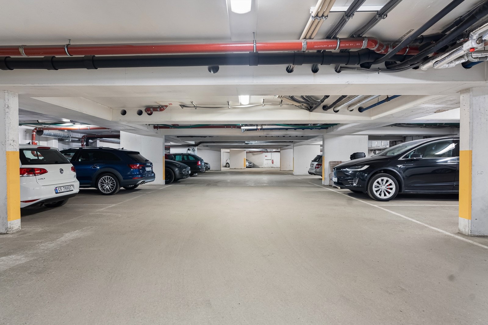 Boligen disponerer to garasjeplasser side om side i sameiets kjeller. Det er montert elbillader på den ene plassen, men kan brukes av begge. Galleribilde