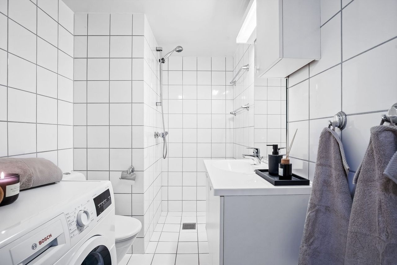 Flislagt baderom med vaskemaskin som medfølger. Galleribilde