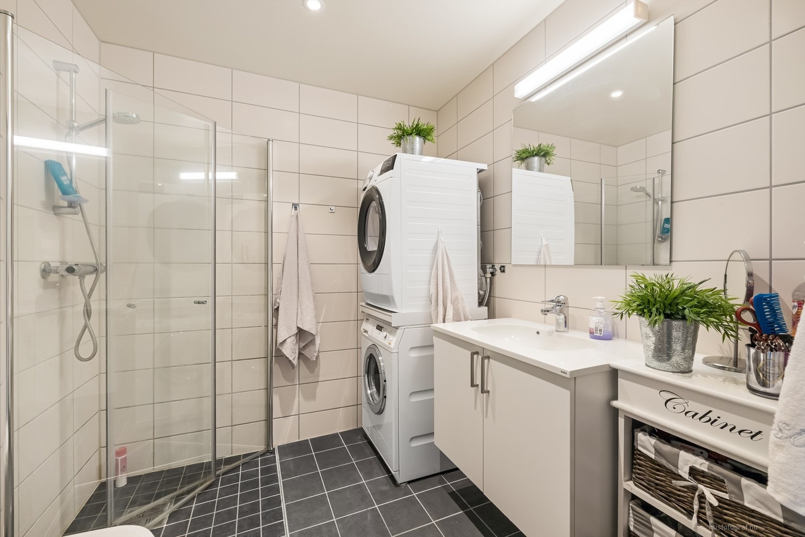 Delikat flislagt bad med heldekkende servant, vegghengt toalett, dusjhjørne og opplegg for vaskemaskin Galleribilde