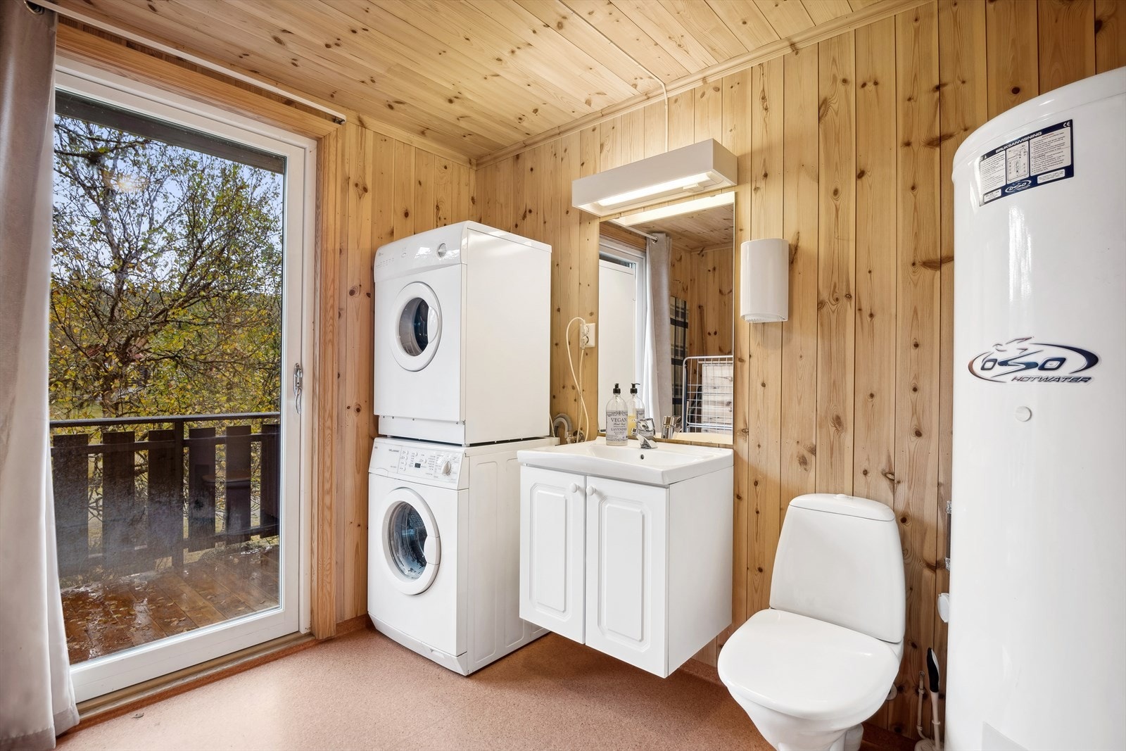 Vaskerommet er innredet med servant på innredning, speil med belysning og opplegg for vaskemaskin. Galleribilde