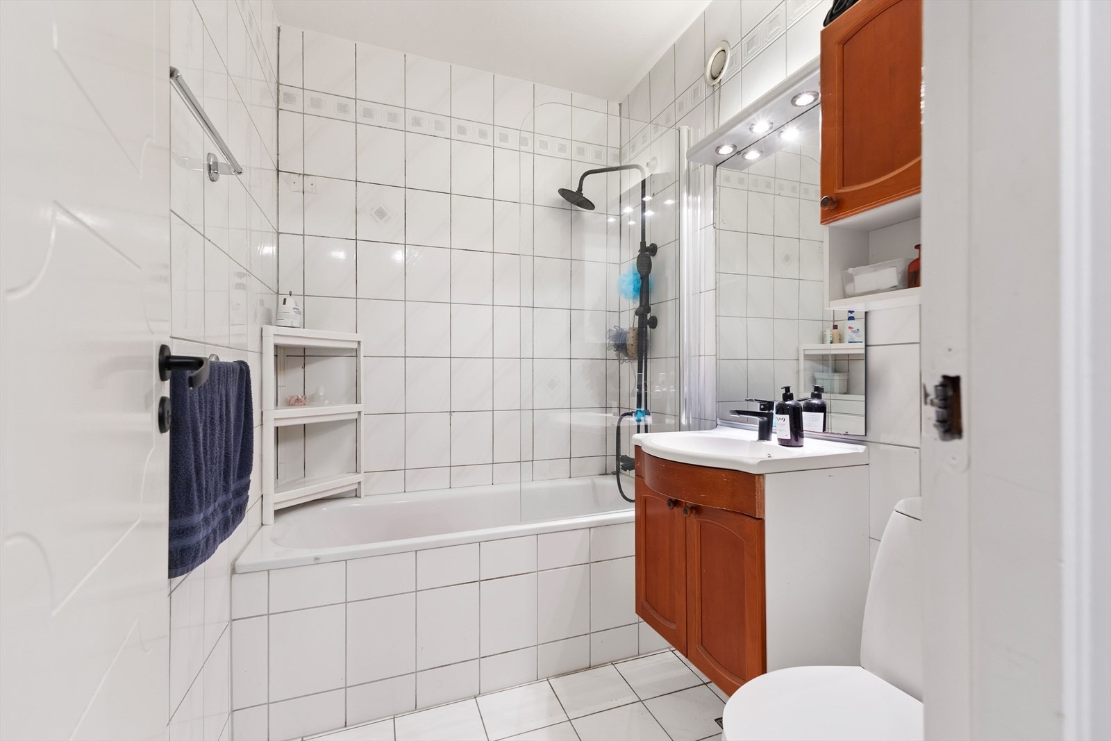 Lyst flislagt bad innredet med badekar, servant med innredning og toalett Galleribilde