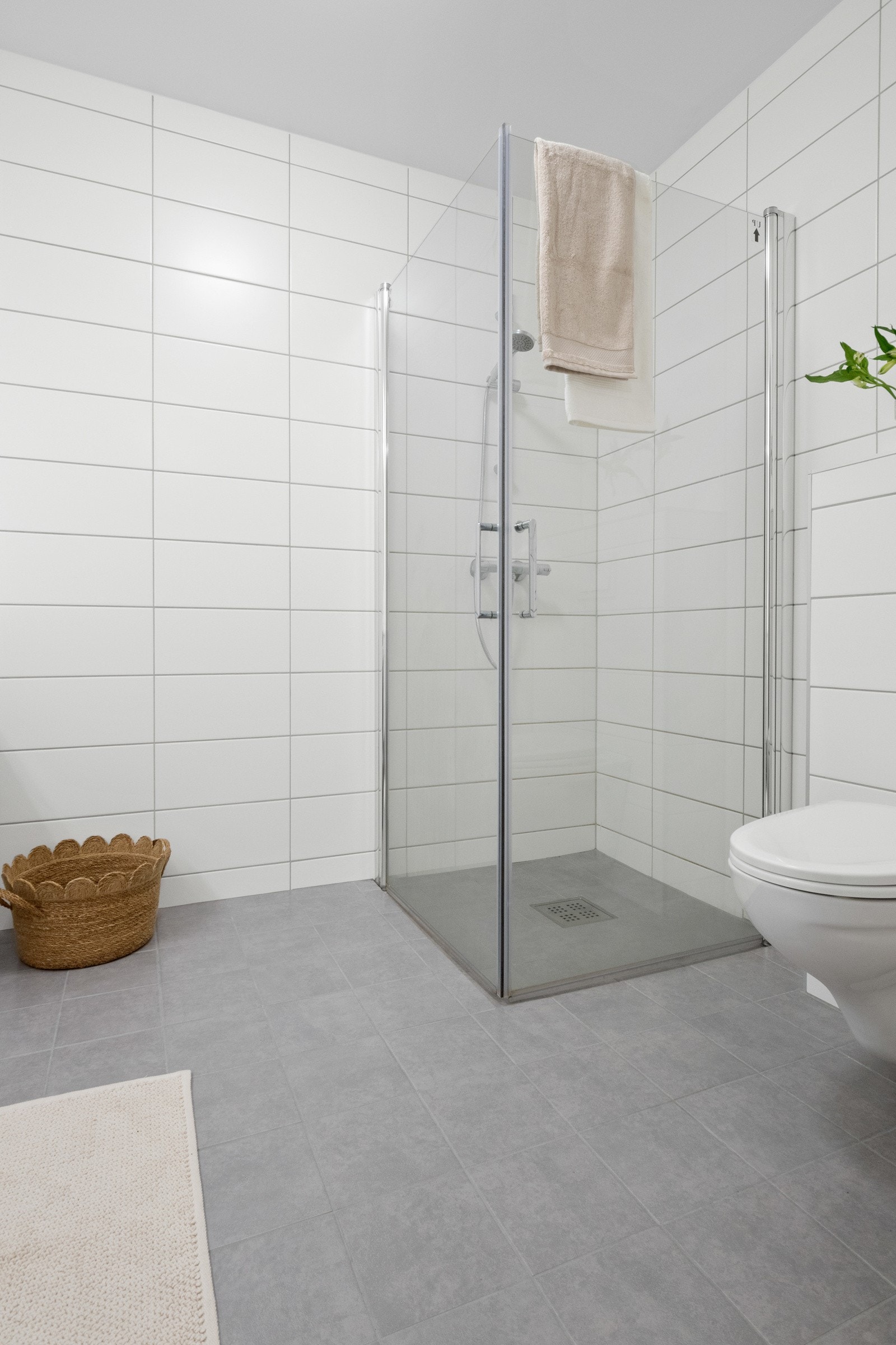 Rommet har grå fliser på gulv med gulvvarme, hvite fliser på veggene og listefri, hvitmalt himling med lampe. Galleribilde